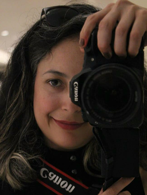 Ericka fotografando, com a câmera em frente ao rosto